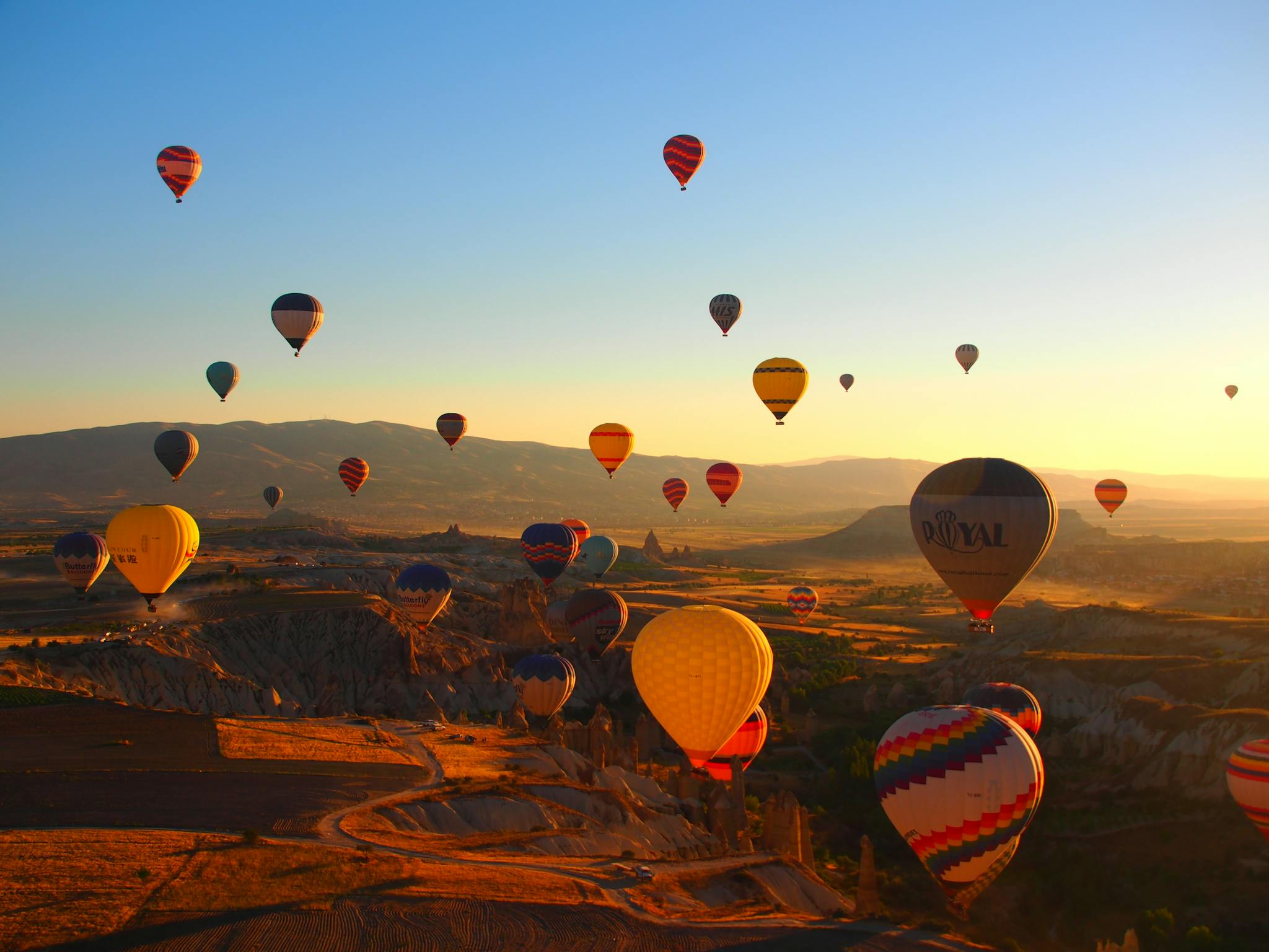 Vibrant hot air balloons soar over Cappadocia's breathtaking landscape at sunrise, creating a magical scene.